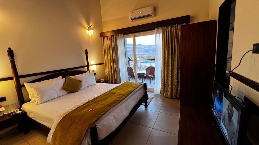 Royal Suite room featuring a large bed with plush bedding and a wide window at Mastiff Grand La Villae Resort, Lonavala
